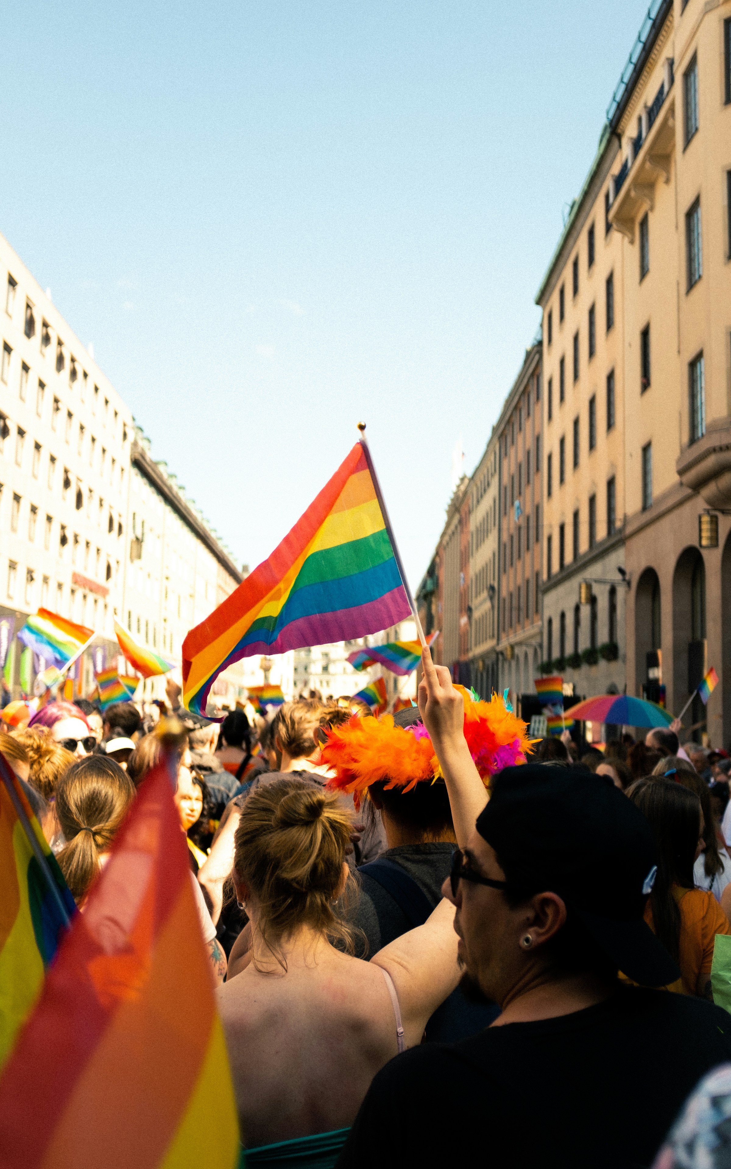 A crowd of people carrying rainbow flags at a Pride march